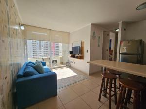 sala de estar con sofá azul y cocina en Oceana Suites Marina Del Sol en La Serena