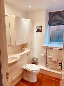a white bathroom with a toilet and a sink at Beautiful spacious old schoolhouse with stunning sea views and beach nearby in Port Bannatyne