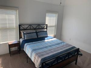 a bed in a bedroom with two windows at 4Bed 2Bath Entire Home 
