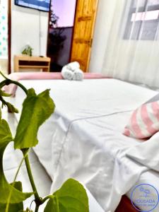a bed with a white sheets and a plant at Pousada Grão de Areia in Búzios