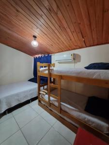 a room with two bunk beds and a wooden ceiling at Ohana's Flat Maresias in São Sebastião