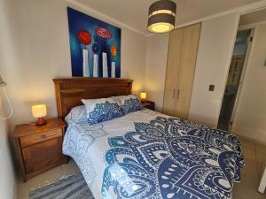 a bedroom with a bed with a blue and white comforter at Oceana Suites Marina Del Sol in La Serena