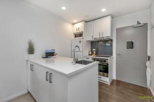 a white kitchen with a sink and a refrigerator at QV Comfortable Downtown Apartment - 1136 in Auckland