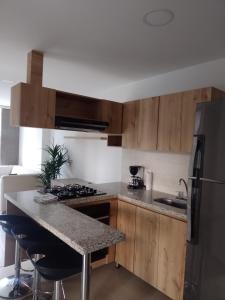 a kitchen with wooden cabinets and a granite counter top at Cozy Apartment in Pinares de San Martin. ¡PEREIRA! in Pereira