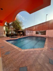 a large swimming pool in a courtyard with an umbrella at JAR villa in Al Kura