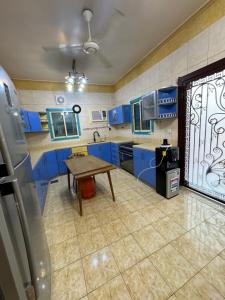 a kitchen with blue cabinets and a wooden table at JAR villa in Al Kura