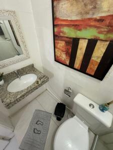 La salle de bains est pourvue de toilettes, d'un lavabo et d'une peinture. dans l'établissement Caminho das Pedras Búzios, à Búzios