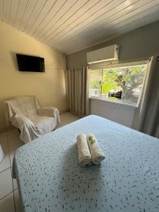 a bedroom with a bed and a chair and a window at Caminho das Pedras Búzios in Búzios