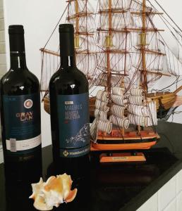 dos botellas de vino junto a un barco en miniatura en Village Shalom Casa 6 - Porto de Sauipe, en Porto de Sauipe