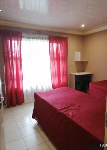 - une chambre avec un lit rouge et une fenêtre dans l'établissement GLOBAL PRIDE, à Soweto
