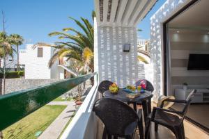 d'un balcon avec une table, des chaises et une télévision. dans l'établissement Precioso apartamento en el centro de Las Américas a 100 metros de la playa, à Playa de las Americas