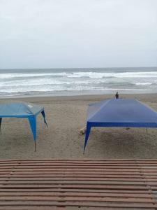 two blue umbrellas on a beach with the ocean at Hospedaje Rulos: Playa Yaya Las Salinas Chilca in Salinas