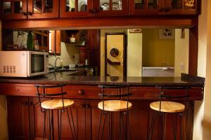 a kitchen with a counter with three bar stools at Elisa Posada Hotel in Córdoba