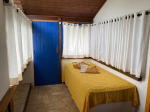 a bedroom with a blue door and a yellow bed at Casa na Colina de Geribá, Búzios in Búzios
