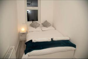 a white bedroom with two beds with a window at Luxury two bedroom apartment in Wilpshire