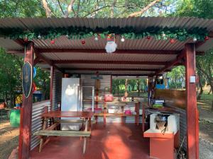 a wooden pergola with a table and a refrigerator at Cabañas Casa Soley in Puerto Soley