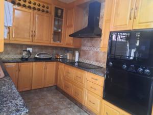 uma cozinha com armários de madeira e um frigorífico preto em 540 BIRSTON em Pretoria