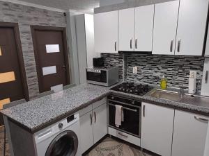 a kitchen with white cabinets and a washer and sink at Pleasure Palace in Sovata