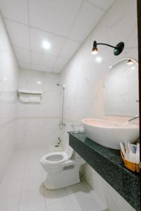 a bathroom with a sink and a toilet and a mirror at Lotus Rock Hotel Đà Nẵng in Da Nang