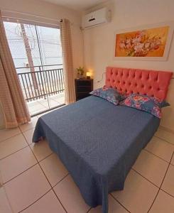 Schlafzimmer mit einem großen Bett mit einem roten Kopfteil in der Unterkunft Aconchegante apto, quadra do mar, no Tabuleiro! in Barra Velha