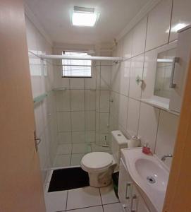 a white bathroom with a toilet and a sink at Aconchegante apto, quadra do mar, no Tabuleiro! in Barra Velha