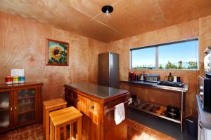 cocina con nevera, mesa y ventana en The shed with a view, en Mahana