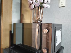 un vaso di fiori seduto sopra un forno a microonde di B25新宿最中心 新宿站10分-Shinjuku center 10 mins to Station, Max 4 直达新宿 涉谷 表参道 池袋 上野 代代木 银座 原宿 a Tokyo