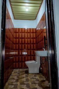 a bathroom with a toilet and brown tiled walls at robiants apartment in Kinatilan