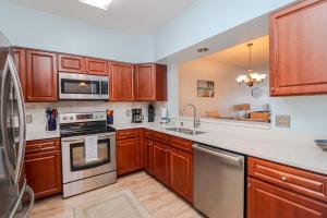 a kitchen with wooden cabinets and stainless steel appliances at Seaside at Anastasia C203 in St. Augustine