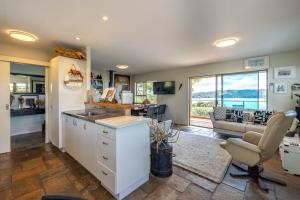 a kitchen with a sink and a desk with a chair at Kennedy Point Seascape in Putaki Bay