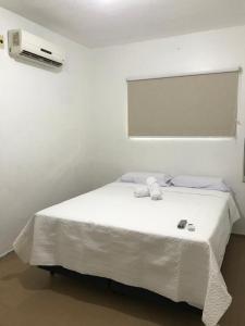 a white bed in a room with a window at Pousada Linhares in João Pessoa