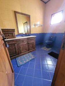 W wyłożonej niebieskimi kafelkami łazience znajduje się umywalka i lustro. w obiekcie Villa Bukit Cipendawa Cipanas w mieście Cipanas