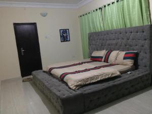 uma grande cama cinzenta num quarto com cortinas verdes em 1 bedroom apartment em Ibadan
