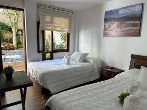a bedroom with two beds and a window at Casa Hotel El Encanto de Villa in Villa de Leyva