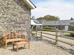 a wooden bench sitting in front of a stone building at Pipistrelle Cottage - Uk34447 in Mathry
