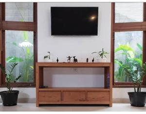 - une télévision dans le salon avec deux fenêtres dans l'établissement VilaDewaScaAcomodation, à Ubud