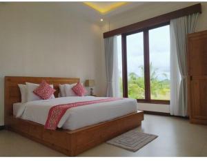 - une chambre avec un grand lit et une grande fenêtre dans l'établissement VilaDewaScaAcomodation, à Ubud