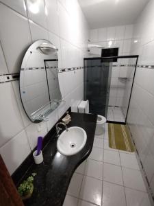 uma casa de banho com um lavatório, um espelho e um WC. em Casa e Lazer em Colina de Laranjeiras em Serra