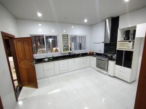 uma grande cozinha com armários brancos e electrodomésticos pretos em Casa e Lazer em Colina de Laranjeiras em Serra