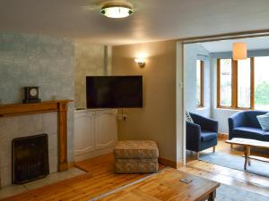 sala de estar con chimenea y TV de pantalla plana en Elesa Cottage, en Elsing