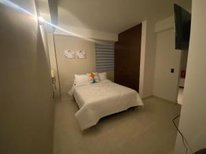 Un pequeño dormitorio con una cama blanca en una habitación en Hermoso apartaestudio San fernando, en Cali