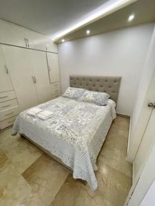 Dormitorio pequeño con cama y armarios blancos en Comodo Apartamento frente al Aeropuerto Maiquetia, en Catia La Mar