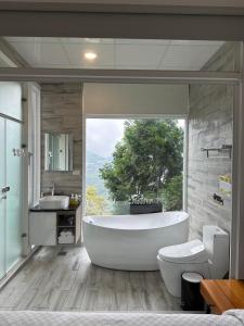 baño con bañera grande y ventana grande en SunSweet House, en Fanlu
