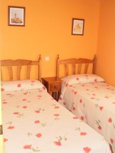 2 camas individuales en una habitación con paredes de color naranja en Los Olmos Holiday Home, en Fuentidueña