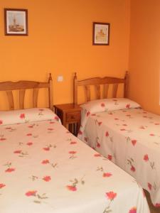 2 Betten in einem Zimmer mit orangefarbenen Wänden in der Unterkunft Los Olmos Holiday Home in Fuentidueña