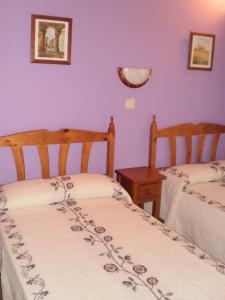2 Betten in einem Zimmer mit lila Wänden in der Unterkunft Los Olmos Holiday Home in Fuentidueña