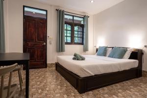1 dormitorio con cama con almohadas azules y escritorio en Lanta School Beach Resort, en Phra Ae beach