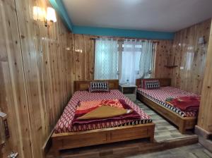 two beds in a room with wooden walls at KACEY HOMESTAY in Pedong
