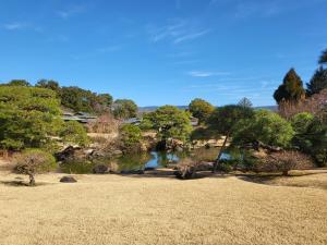vistas a un estanque en un parque con árboles en Sanyo-so, en Izunokuni