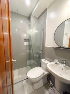 a bathroom with a toilet and a sink and a mirror at Koze Suites in Dumaguete